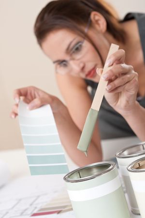 Female designer with can of paint choosing color at officeの写真素材