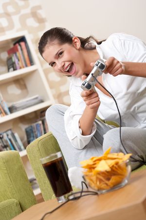 Students - Female teenager playing video game holding game pad in living roomの写真素材
