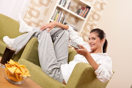Students - Happy female teenager with potato chips  in modern living roomの写真素材