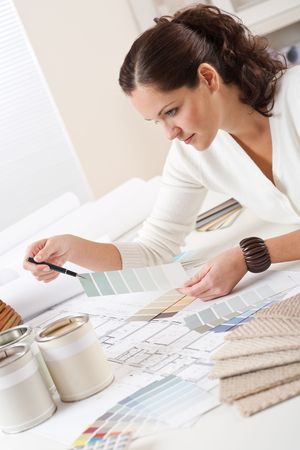 Young female interior designer working at office with color swatch and can of paintの写真素材