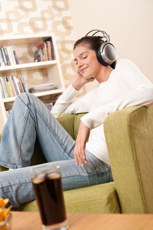 Students - Happy female teenager with headphones listening to music in modern loungeの写真素材
