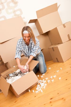 Moving house: Happy woman unpacking box in new home, kitchen, pots and pansの写真素材