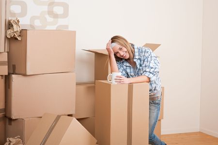 Moving house: Woman with box in new home having cup of coffeeの写真素材