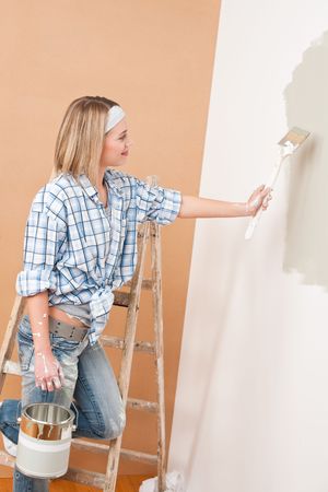 Home improvement: Smiling woman with paint and brush painting wallの写真素材