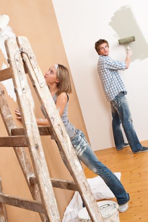 Home improvement: Young couple painting wall with paint rollerの写真素材