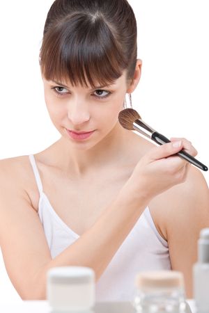 Body care: Young woman applying powder with make-up brush on white backgroundの写真素材