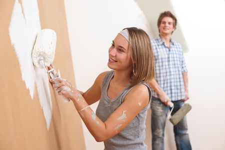 Home improvement: Young man and woman painting wall with paint rollerの写真素材