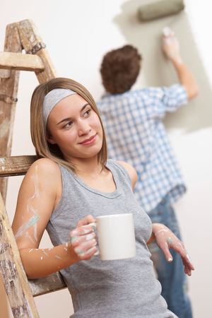 Home improvement: Young couple painting wall with paint rollerの写真素材