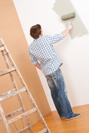 Home improvement: Young man with paint roller and ladderの写真素材