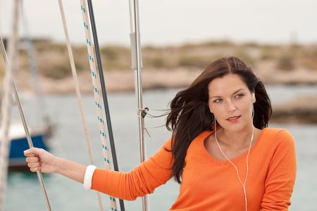Attractive woman standing on sailing boat holding ropeの写真素材