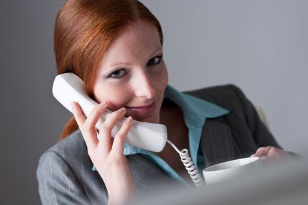 Successful business woman on the phone with cup of coffeeの写真素材