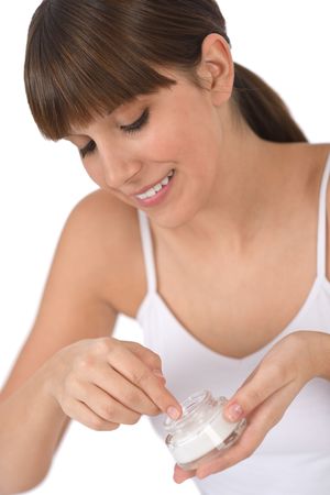 Body care - Female teenager applying moisturizer cream on faceの写真素材