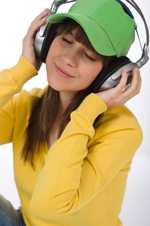 Happy female teenager enjoy music on white background, with headphones and baseball capの写真素材