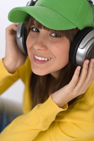 Happy female teenager enjoy music on white background, with headphones and baseball capの写真素材