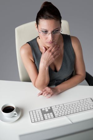 Successful business woman at office having cup of coffee sitting at computer deskの写真素材