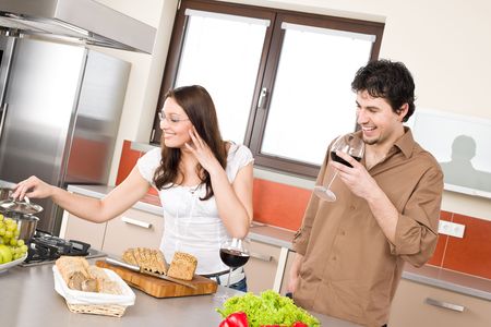 Happy couple cook together in modern kitchen, drink red wineの写真素材