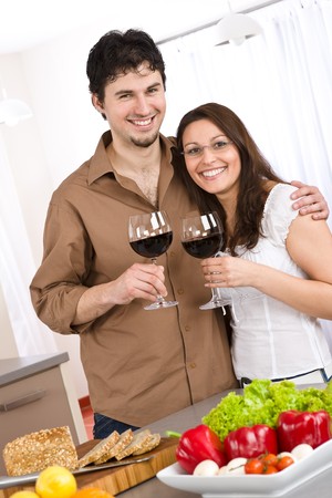 Happy couple drink red wine in modern kitchen togetherの写真素材