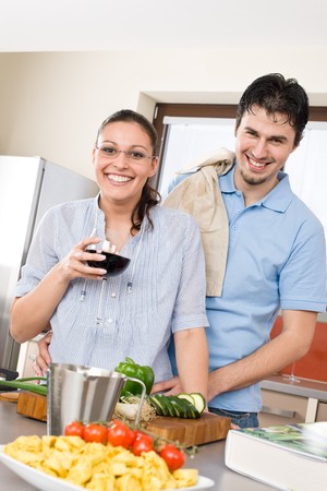 Cheerful couple in modern kitchen cook together, drink red wineの写真素材