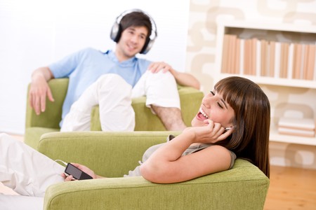 Student - Happy teenagers listen to music sitting on green armchair, holding mp3 playerの写真素材