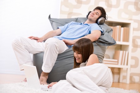 Student - Happy teenager with laptop and headphones relaxing in loungeの写真素材