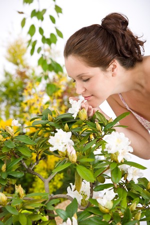 Portrait of woman smelling blossom of Rhododendron flower  on white backgroundの写真素材