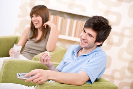 Student - happy teenagers watching television holding remote controlの写真素材