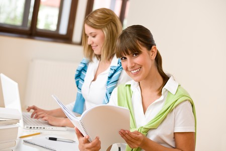 Student at home - two happy woman with laptop and book studyの写真素材
