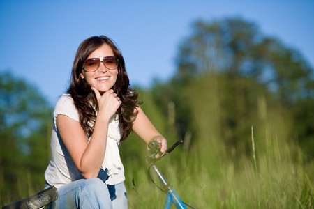 Woman with old-fashioned bike in summer meadow on sunny dayの写真素材