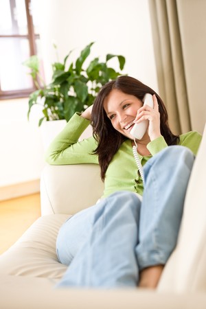 On the phone home: Happy woman calling, plant in backgroundの写真素材