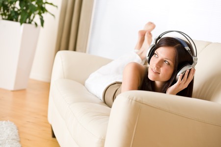 Woman with headphones listen to music in lounge, plant in backgroundの写真素材