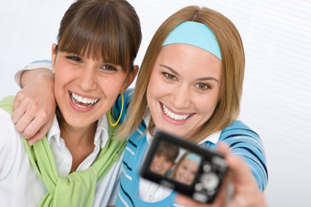 Two young happy woman taking their picture with camera