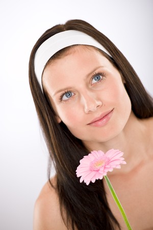 Beautiful woman holding gerbera daisy flower with white headbandの写真素材
