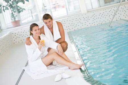 Swimming pool - young happy couple relax on poolside in luxury hotelの写真素材