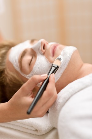 Male beauty - man having facial mask in luxury spa centerの写真素材