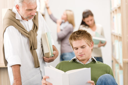 Library - student with mature professor at high school with bookの写真素材