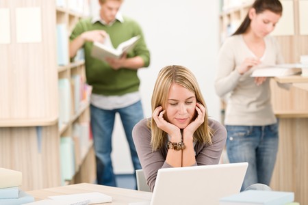 High school library - female student with laptop and bookの写真素材