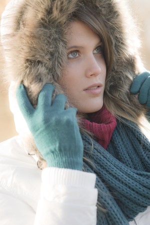 Winter fashion - woman with fur hood and gloves outside, desaturated colorsの写真素材