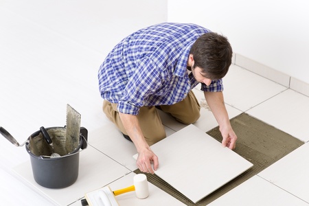 Home improvement, renovation - handyman laying tile, trowel with mortarの写真素材