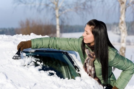 Winter car - woman remove snow from windshield with ice scraperの写真素材