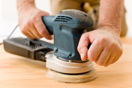 Home improvement - handyman sanding wooden floor in workshopの写真素材