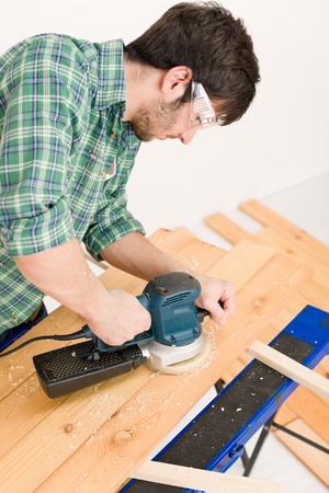 Home improvement - handyman sanding wooden floor in workshopの写真素材