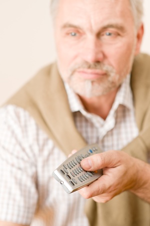 Senior mature man holding remote control in handの写真素材