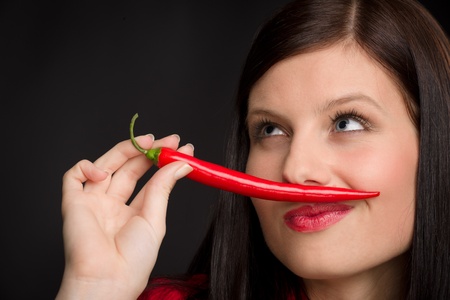 Chili pepper - portrait young woman bite red spicy vegetableの写真素材