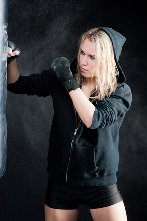 Blond boxing woman in black training with punching bagの写真素材