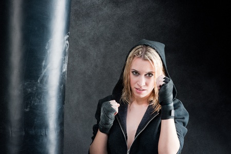 Blond boxing woman in black training with punching bagの写真素材