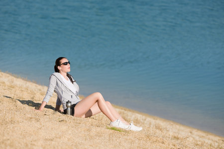 Summer active woman sit on beach sunset in fitness outfit