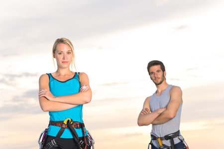 Rock climbing active young mountaineers reach top at sunsetの写真素材