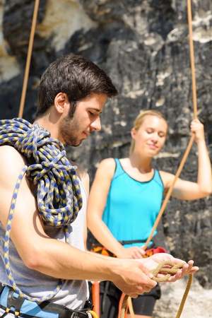 Rock climbing active young man showing mountaineer woman rope knotの写真素材