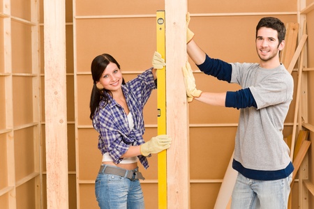 Home improvement smiling young couple fixing wall with spirit levelの写真素材