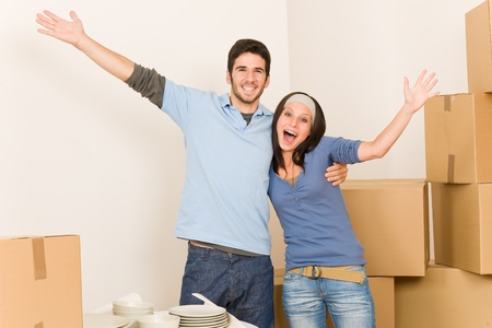 Moving new home young cheerful couple unpacking cardboard boxes togetherの写真素材